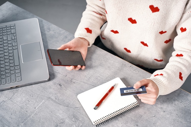 Mãos de mulher com telefone vermelho e compras com cartão de crédito online