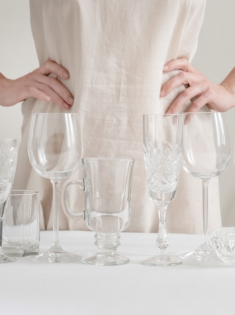 Mãos de mulher com um diferentes copos de vinho em cima da mesa no branco
