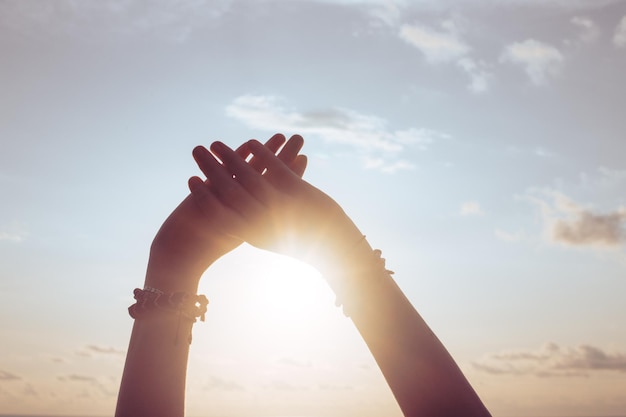 Mãos de mulher contra o céu azul e sol