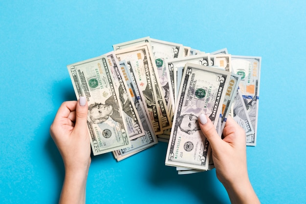 Mãos de mulher de negócios contando cinco e outras notas de dólar em fundo colorido. Salário e conceito de vencimento. Vista superior do conceito de investimento.