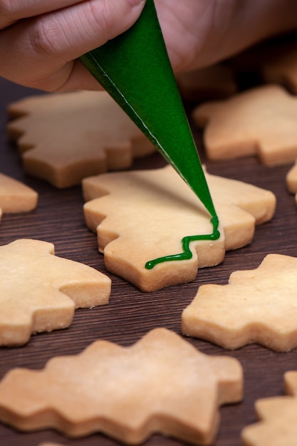 Mãos de mulher desenhando um biscoito de Natal de gengibre