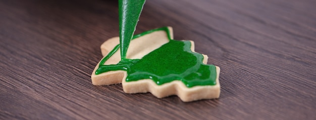 Mãos de mulher desenhando um biscoito de Natal de gengibre