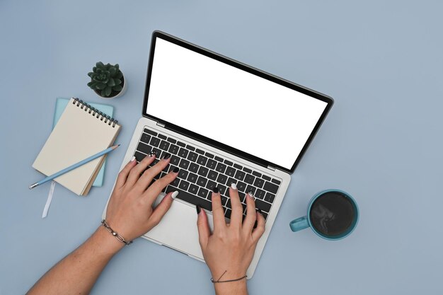 Mãos de mulher digitando no laptop sobre fundo azul