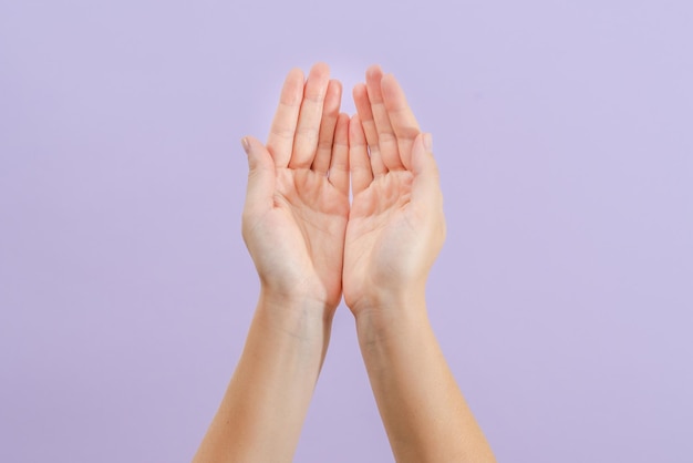 Mãos de mulher em fundo lilás Cuidados com a pele para manicure e tratamento de beleza