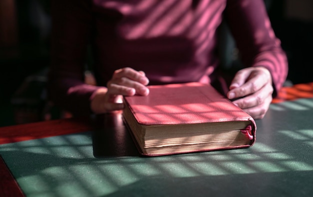 Mãos de mulher em uma bíblia fechada em uma mesa