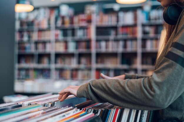 Mãos de mulher escolhendo disco de vinil na loja de discos de música