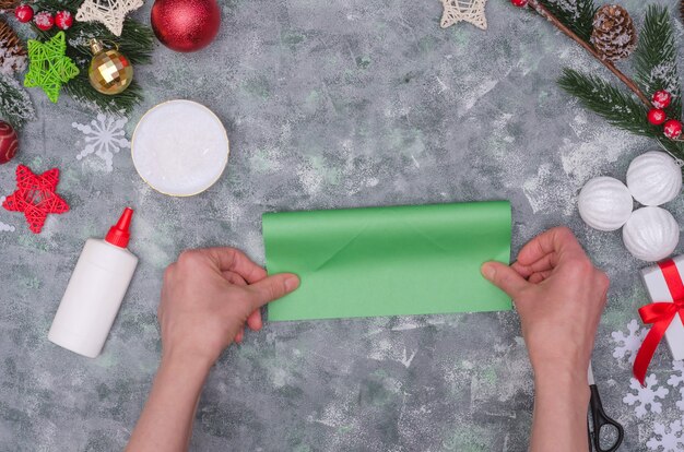 Mãos de mulher fazendo uma decoração artesanal de Natal