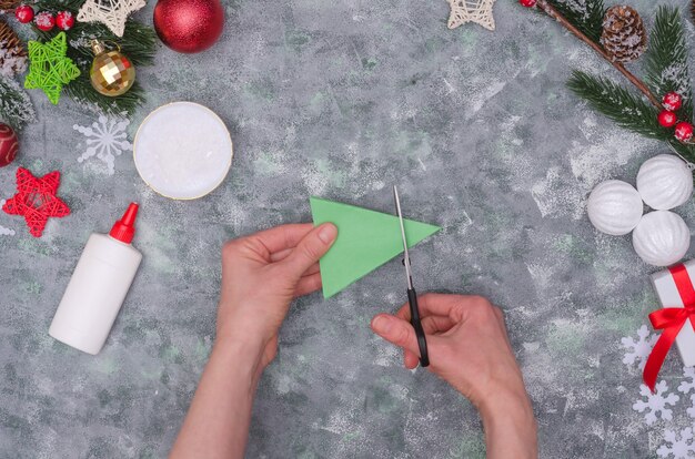 Mãos de mulher fazendo uma decoração artesanal de Natal