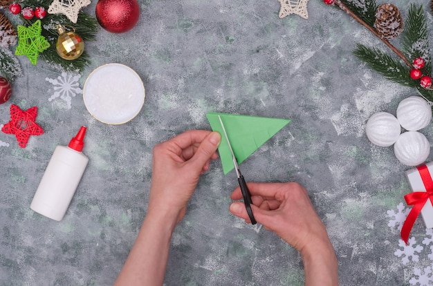 Mãos de mulher fazendo uma decoração artesanal de Natal