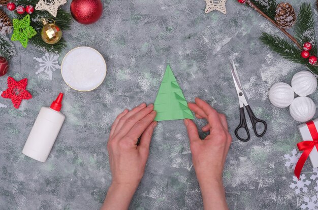 Mãos de mulher fazendo uma decoração artesanal de Natal