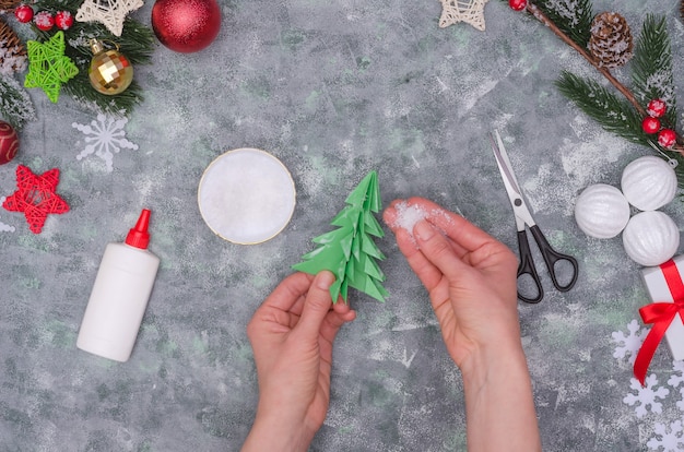 Mãos de mulher fazendo uma decoração artesanal de Natal