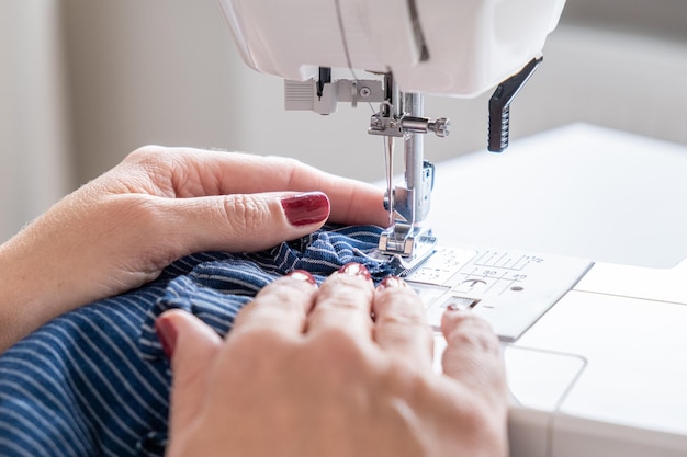 Mãos de mulher fecham costura em material de tecido de costura à máquina