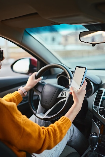 Mãos de mulher irreconhecível motorista usando maquete de tela branca enquanto dirige
