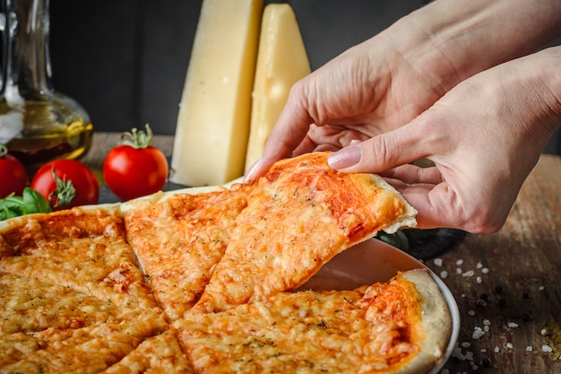 Mãos de mulher leva um pedaço de pizza