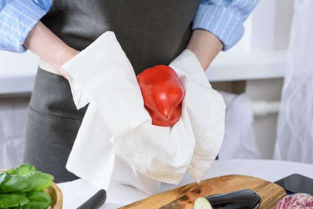 Mãos de mulher limpam pimenta vermelha com pano de prato branco cozinhando em casa conceito