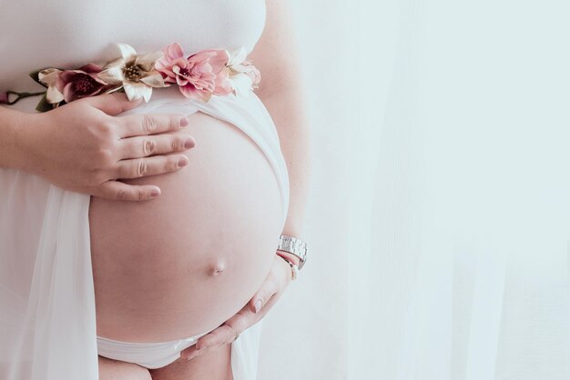 Mãos de mulher na barriga grávida.