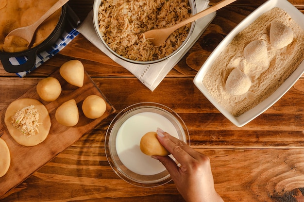 Mãos de mulher preparando croquete brasileiro