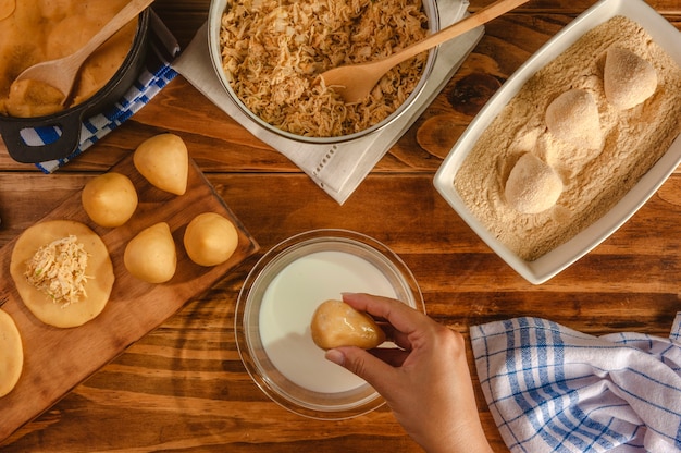 Mãos de mulher preparando croquete brasileiro