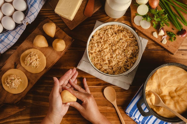 Mãos de mulher preparando croquete brasileiro