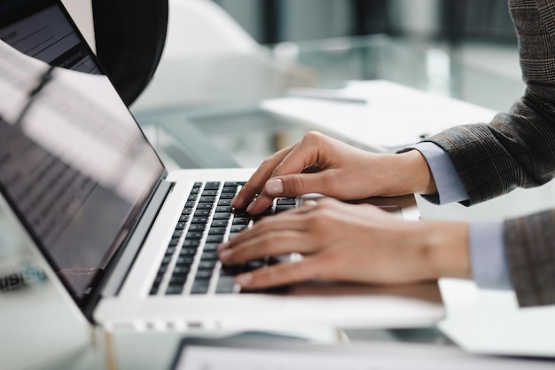 Mãos de mulher pressionando teclas em um teclado de laptop no escritório