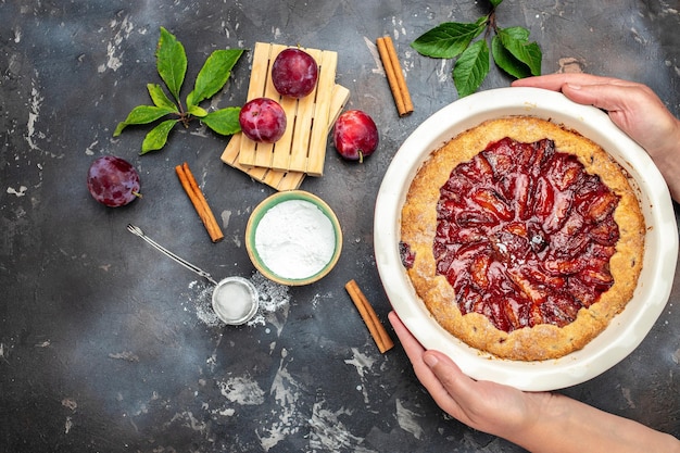 Mãos de mulher seguram torta de ameixa Conceito de padaria culinária culinária para vista superior do texto