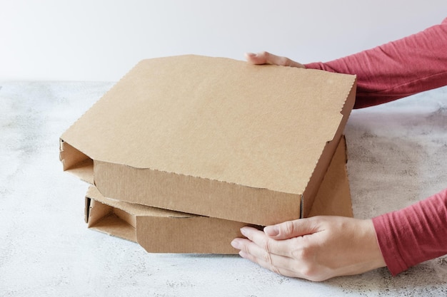 Mãos de mulher segurando caixas de pizza de papelão na mesa sobre fundo branco