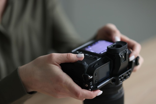 Mãos de mulher segurando câmera fotográfica profissional com fotógrafo de tela pequena verificando fotos