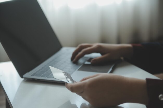 Mãos de mulher segurando e usando cartão de crédito para fazer compras online