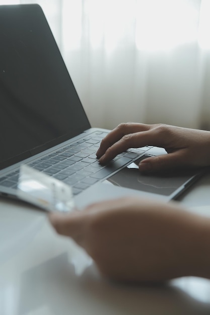 Mãos de mulher segurando e usando cartão de crédito para fazer compras online