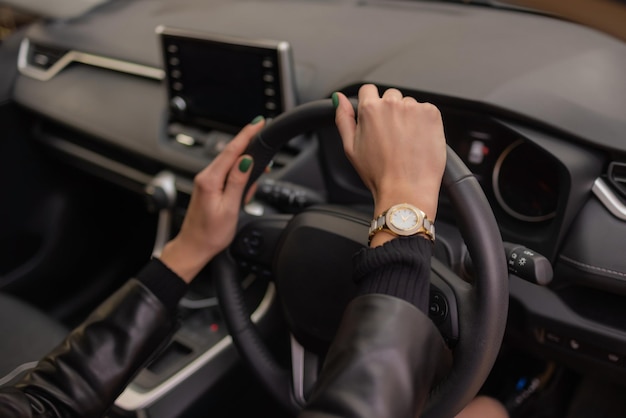 Mãos de mulher segurando o volante de um carro novo no showroom