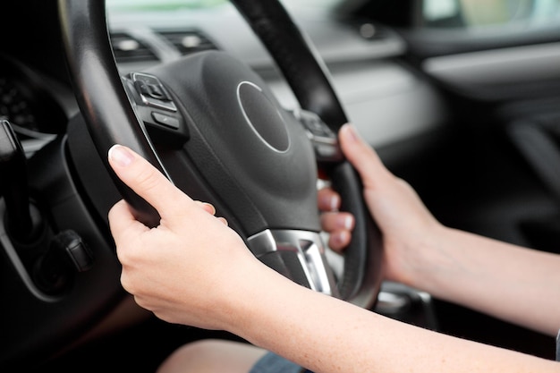 Mãos de mulher segurando o volante no carro de luxo