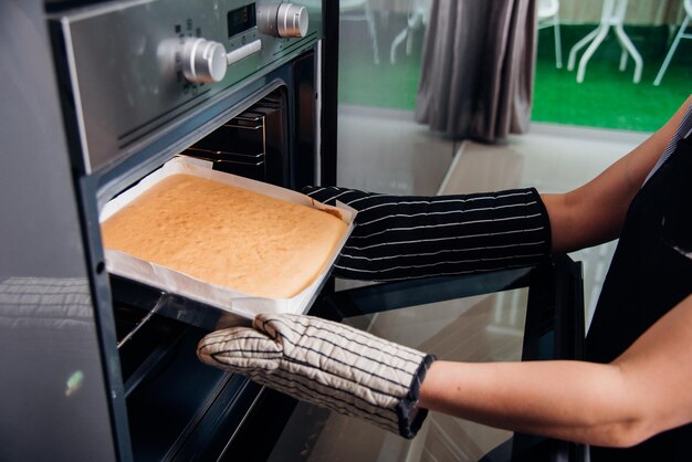 Mãos de mulher segurando pão de massa na frente do forno