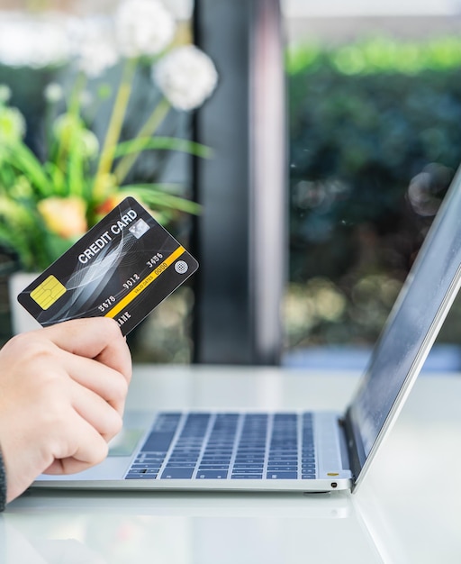 Mãos de mulher segurando um cartão de crédito para compras on-line