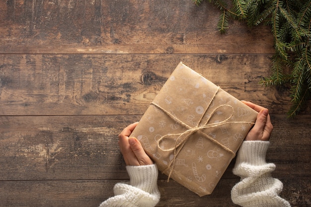 Mãos de mulher segurando um presente de Natal