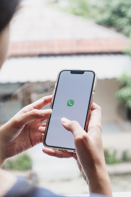 Mãos de mulher segurando um smartphone com aplicativo messenger whatsapp na tela. menina conversando com