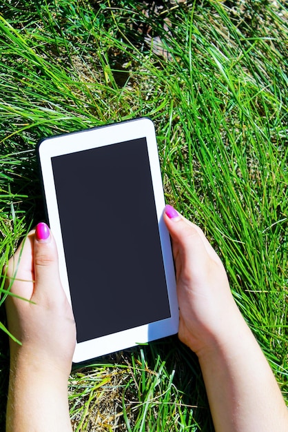 Mãos de mulher segurando um tablet branco com tela em branco em verde gr