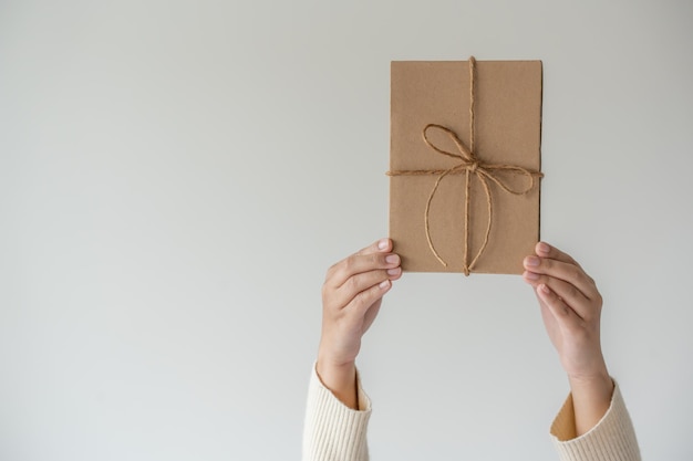 Mãos de mulher segurando uma caixa de presente com um laço de fita Conceito minimalista de dar um presente