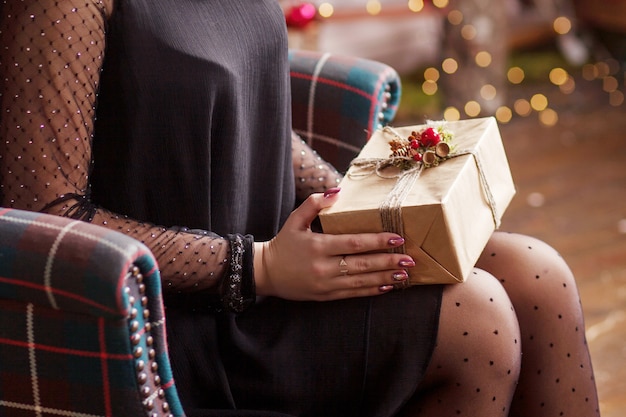 Mãos de mulher segurando uma caixa de presente ouro. cena festiva com bokeh.