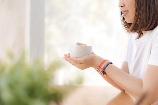 Mãos de mulher segurando uma xícara de café branco