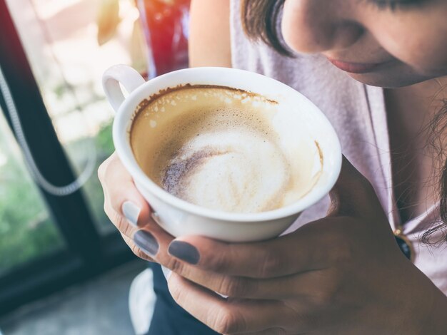 Mãos de mulher segurando uma xícara de café quente branco