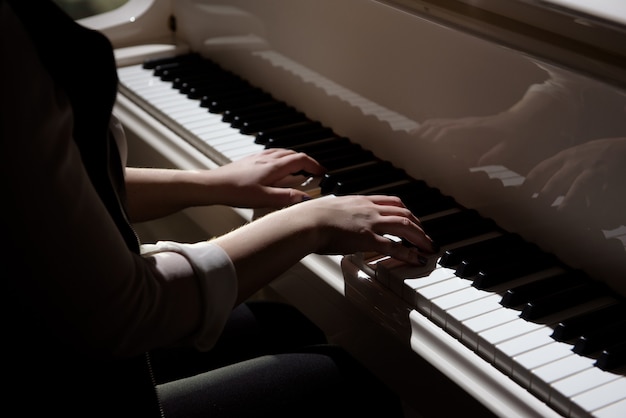 Mãos de mulher tocando um piano, instrumento musical