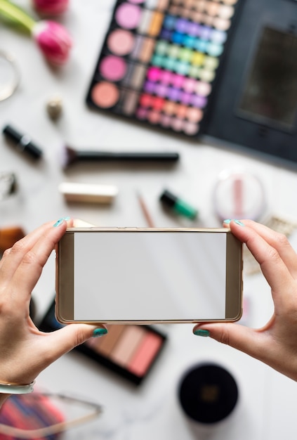 Mãos de mulher usando celular foto de captura com fundo de cosméticos