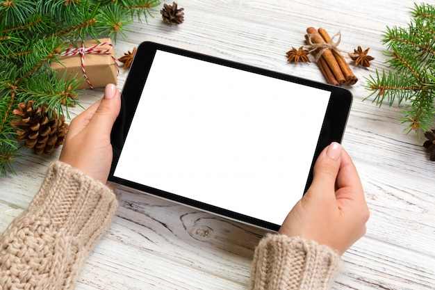 Mãos de mulher usando computador tablet na mesa de madeira mesa, cristmas tempo de compras, feliz Natal simulado acima, vista superior