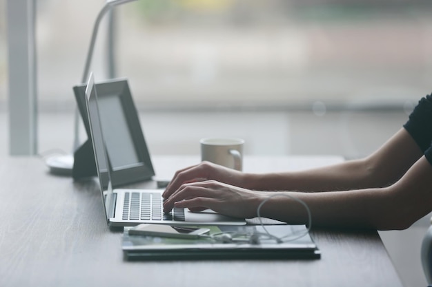 Mãos de mulher usando laptop na mesa