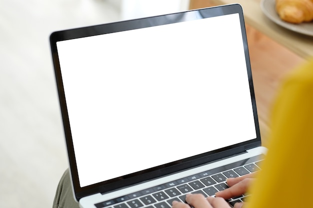 Mãos de mulher usando o computador portátil com tela em branco