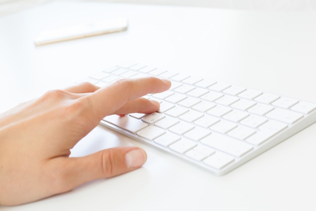 Mãos de mulher usando o teclado no escritório