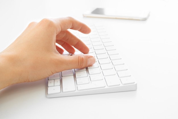 Mãos de mulher usando o teclado no escritório