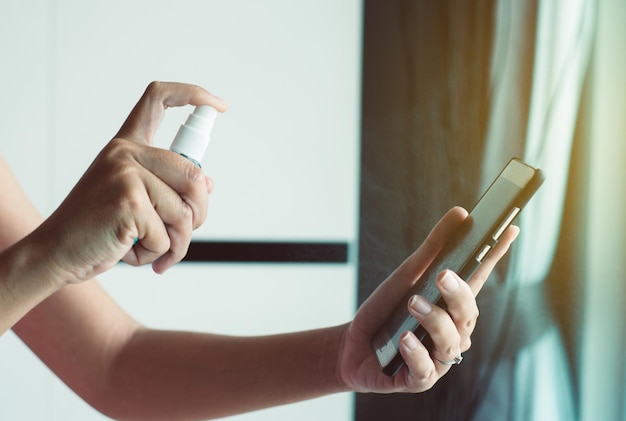 Mãos de mulher usando spray de álcool para smartphone,medidas preventivas contra coronavírus,covid-19