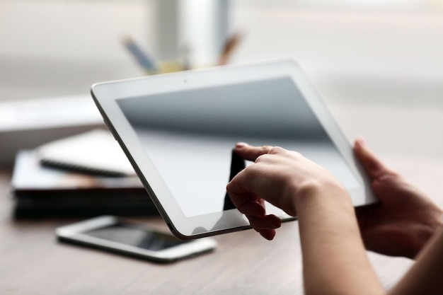 Mãos de mulher usando tablet na mesa