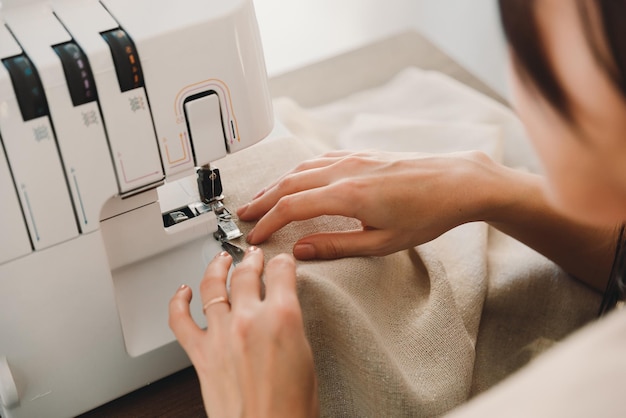 Mãos de mulher usando uma máquina de costura para costurar tecido ou cortinas ou roupas